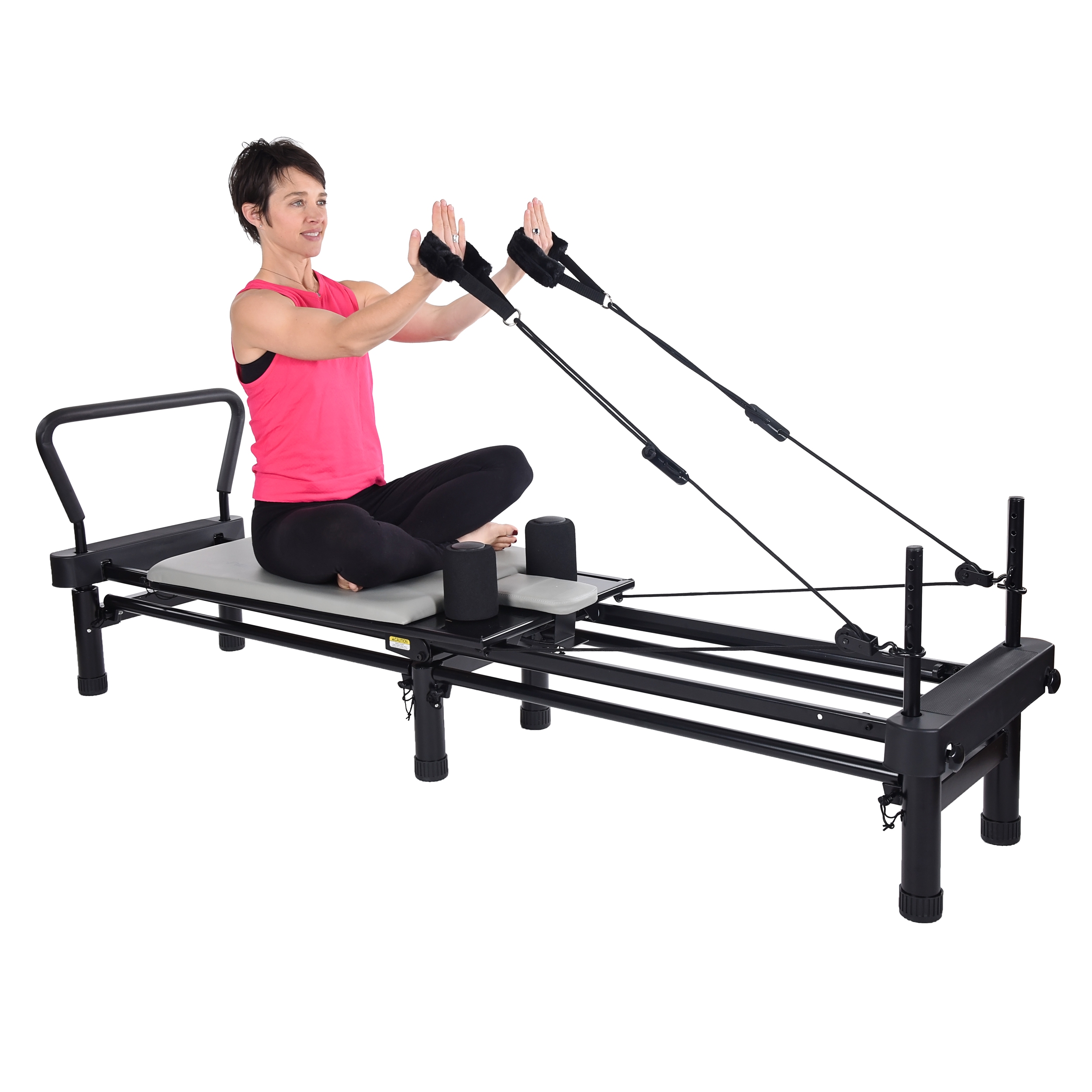 Woman seated cross feet on pilates while pulling the handstraps.