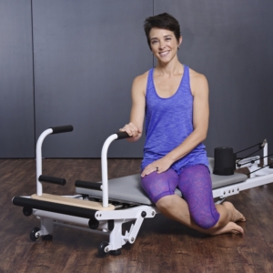 Woman seated and holding the handle bar Pilates.