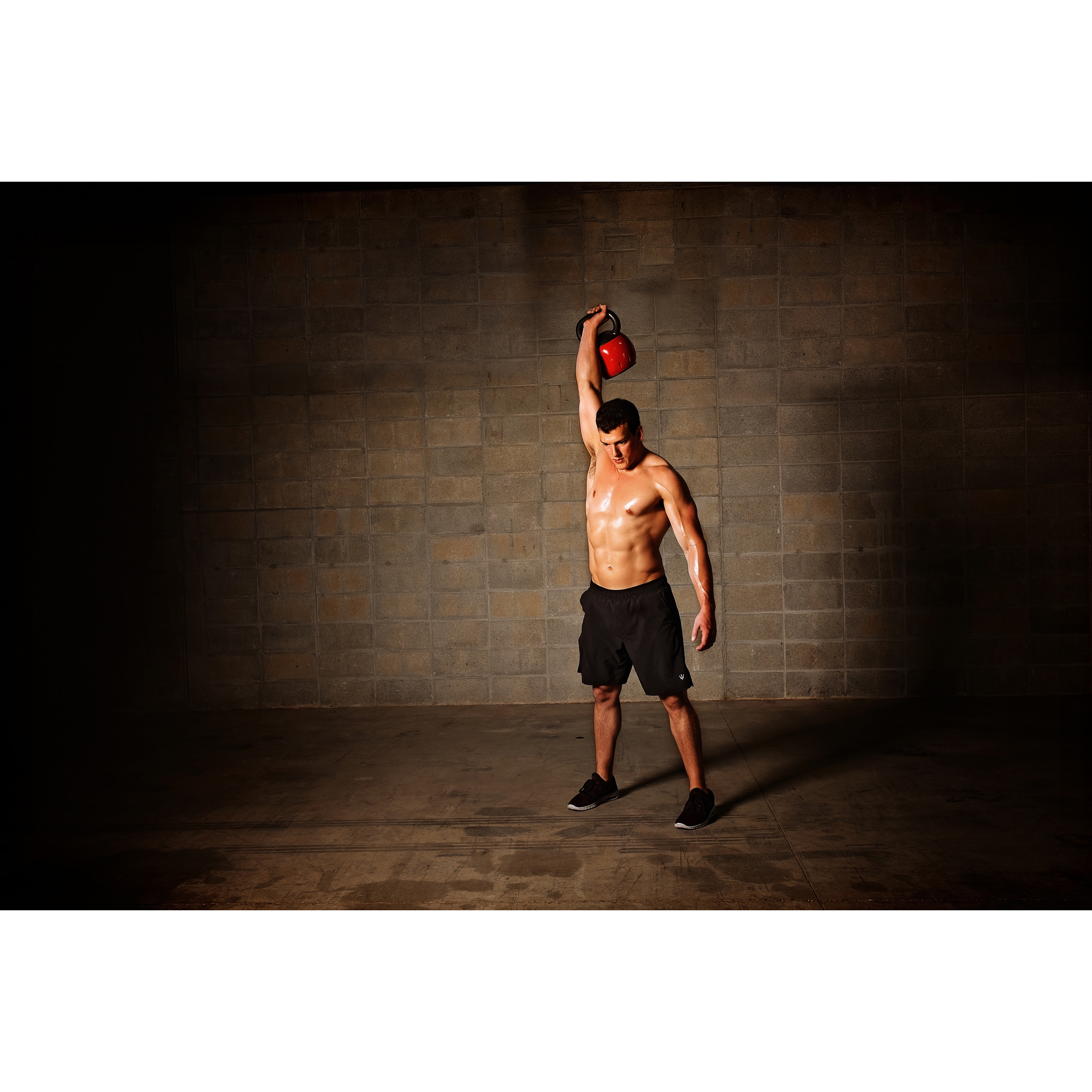 Man standing while pushing upright overhead the Kettle Versa-Bell.