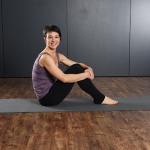 Woman seated smile on Aeropilates Mat.