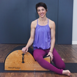 Woman seated on Spine Corrector Barrel.