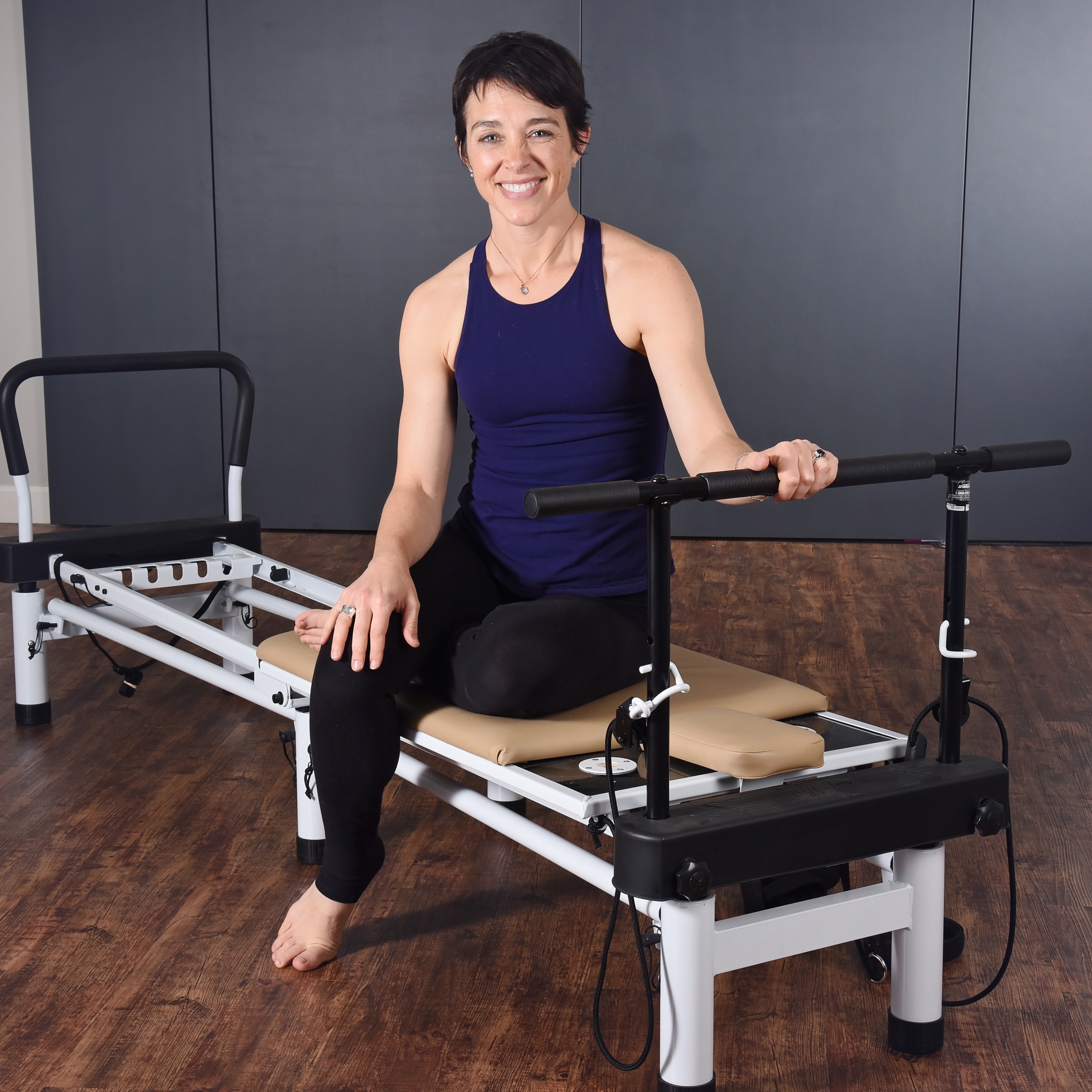 Woman seated on AeroPilates Pull-Up Bar Full Body Workout.