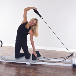Woman curve body while hand pulling the push-handle on pilates.