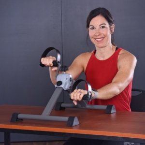 Woman smiling while hands cycling on Upper and Lower Body Machine.